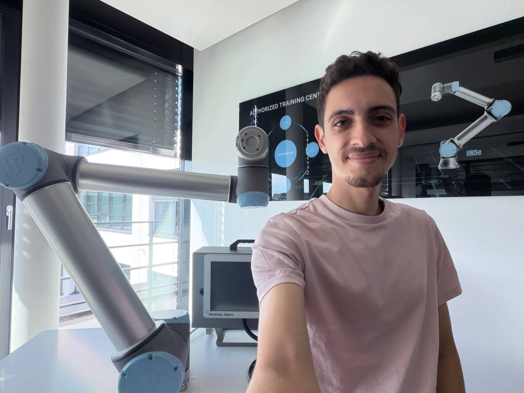 Karim standing alongside a collaborative robot at Universal Robots