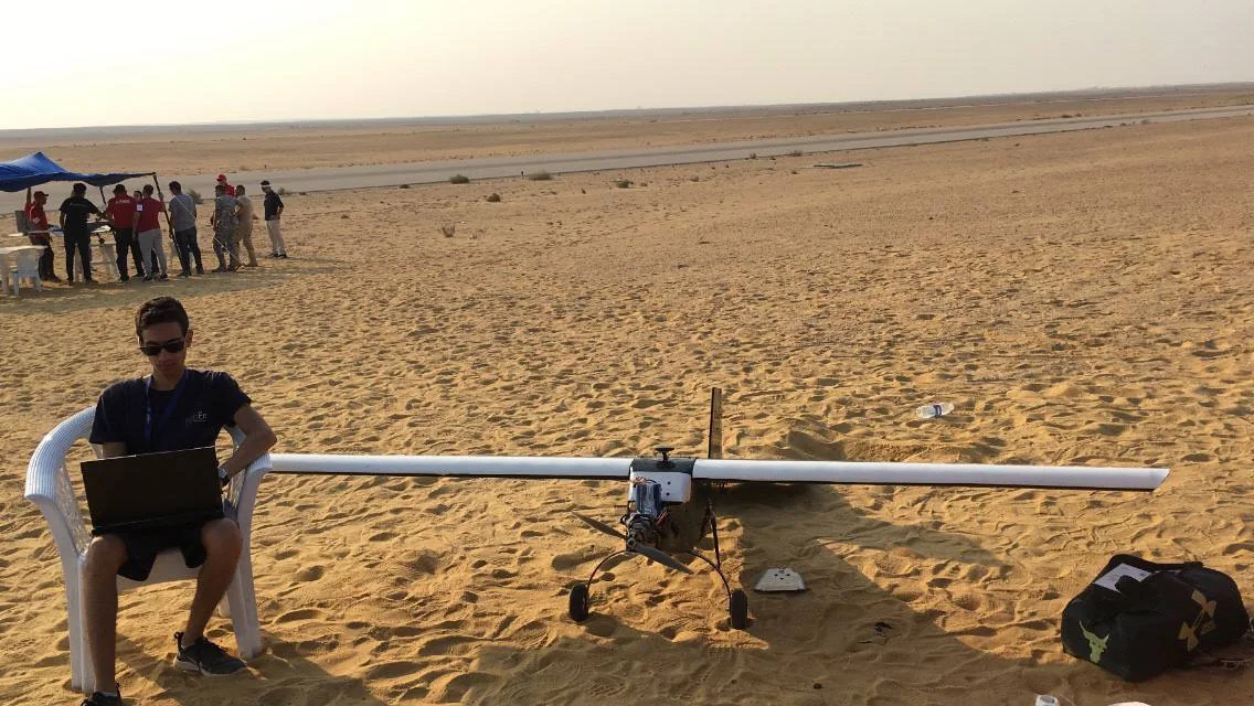 Working on firmware beside a fixed-wing UAV in the desert